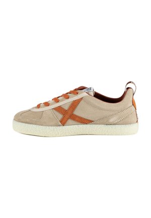 Sneaker in suede beige con lacci arancioni e grande "X" arancione ricamato sul lato, suola bianca strutturata e tirante sul tallone.