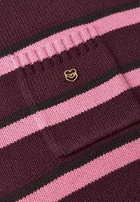 Gros plan d’un tissu tricoté avec des rayures horizontales violet foncé, rose et noires, et une petite épingle dorée en forme de cœur sur une section en relief.