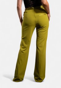 Pantaloni larghi verdi realizzati in un tessuto morbido, con vita media e una singola tasca posteriore, caratterizzati da un design pulito e sartoriale.