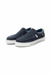 Zapatillas de lona azul marino sin cordones con suelas de goma blanca, que presentan sutiles detalles de costura y un diseño en dos tonos en el cuello.
