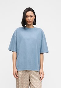 Γαλάζια βαμβακερή μπλούζα oversized με στρογγυλή λαιμόκοψη και κοντά μανίκια, με διακριτική πλυμένη υφή και άνετη εφαρμογή.