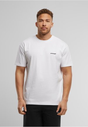 White cotton T-shirt with short sleeves, crew neck, and a small black logo on the left chest area. Paired with black shorts.