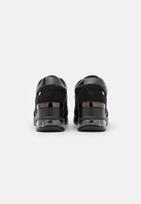 Czarne sneakersy z gładką skórzaną i zamszową cholewką, o zaokrąglonym kształcie, przezroczystej podeszwie oraz z akcentowanymi piętami o błyszczącym wykończeniu.