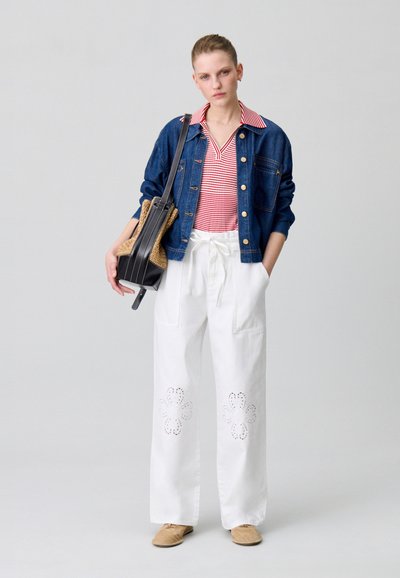Chaqueta de denim, polo a rayas rojo y blanco, pantalones anchos blancos con recortes florales y zapatos beiges tipo slip-on. Bolsa negra sobre el hombro.