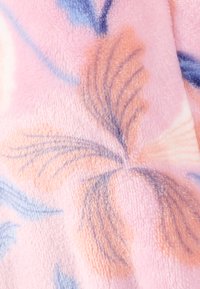 Coperta in pile con una superficie morbida e testurizzata, caratterizzata da uno sfondo rosa pastello e motivi floreali in tonalità blu e arancione.