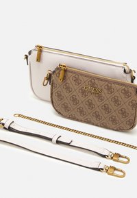 Kaksi olkalaukkua: yksi valkoinen, toinen ruskea logo-kuviolla. Molemmissa on kultaiset vetoketjut ja tarvikkeet. Mukana irrotettava kultaketju ja hihna.