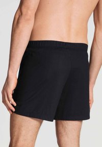 Zwarte zwemshorts van zachte stof, met een elastische tailleband en een losse pasvorm, met een minimalistisch design en geen zichtbare patronen.