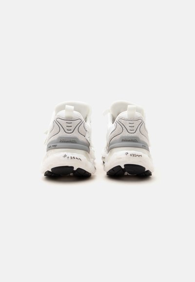 Paire de baskets Dsquared2 blanches et grises vues de dos, avec semelles noires et texte manuscrit sur la semelle intermédiaire.