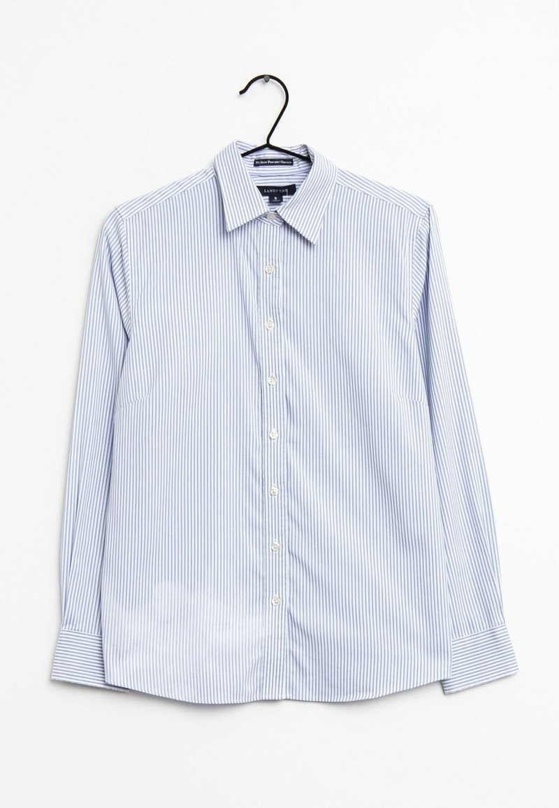Chemise à manches longues boutonnée avec de fines rayures verticales bleues et blanches suspendue à un cintre noir sur fond blanc.