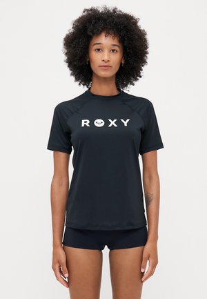 Schwarzes kurzärmeliges Rashguard aus glattem Material mit rundem Halsausschnitt und weißem "ROXY"-Logo auf der Vorderseite. Trägt dazu passende schwarze Unterteile.