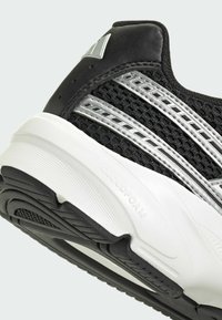 Čierna športová obuv s vrchným materiálom z sieťoviny, striebornými akcentmi, podrážkou Cloudfoam a textúrovaným gumovým dezénom pre lepšiu priľnavosť. Obsahuje dizajn s tromi pruhmi.