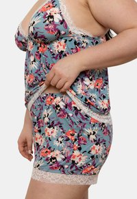 Ensemble de nuit floral avec un fond bleu, des finitions en dentelle et des motifs floraux éclatants en rose, blanc et violet. Tissu doux au fit ample.
