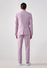 Lavendel dress med skreddersydd design, med en enkelt ventil bak og matchende bukser. Fullført med hvite joggesko.