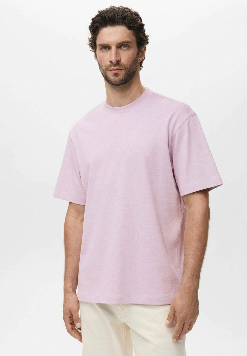 Tricou scurt cu mânecă scurtă de culoare roz deschis, realizat dintr-un material moale, cu guler rotund și o croială relaxată. Design simplu, fără modele sau accente vizibile.