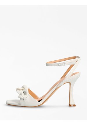Sandalia blanca de tacón alto con punta abierta y correa en el tobillo. Presenta un detalle de nudo en el empeine y un tacón afilado. Acabado en cuero liso.