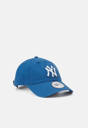 Blå baseballkasket med hvid NY-logo på fronten og en buet skygge, vist på en ensartet lys baggrund.