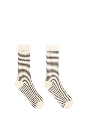 Paire de chaussettes blanches montantes avec fines rayures horizontales noires et talons et orteils unis sur fond blanc.