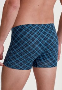 Shorts pour hommes en bleu marine avec un motif à carreaux bleus. Le matériau semble extensible, avec une coupe ajustée, une taille mi-haute et des coutures plates.