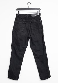 Mustat farkut suoraan lahkeella, joissa on kaksi takataskua, niittejä ja etiketti vyötärön lähellä. Tasainen rakenne koko ajan.