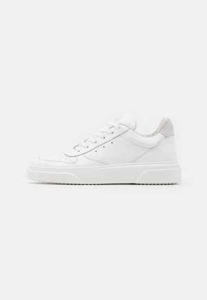 Biały niski skórzany sneaker z sznurowaniem z przodu, teksturowaną podeszwą i wyściółką wokół kostki, pokazany z boku na jednolitym tle.