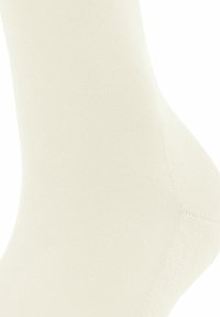 Calza crema fino al ginocchio realizzata in un tessuto liscio e elastico. Presenta una texture a costine e un tallone rinforzato, con una punta senza cuciture per il massimo comfort.