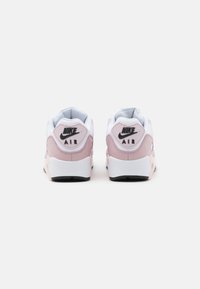 Nike Air sneakers in het wit met roze accenten, voorzien van een getextureerde achterkant, zachte kraag en zwart logo op de hiel. Rubberen zool.