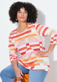 Pitkähiha, monivärinen raidallinen paita punaisessa, oranssissa, pinkissä ja kermassa. Ominaisuuksiin kuuluu pyöreä pääntie ja hienovarainen kiilto geometristen kuvioiden alla.