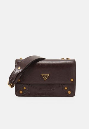 Sac à bandoulière Guess en cuir texturé marron foncé avec une large sangle, des clous dorés et une plaque logo triangulaire sur le rabat avant.