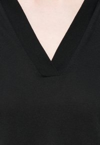 Black v-neck pullover sweater made from ribbed knit fabric, showcasing a deep neckline and a smooth texture.