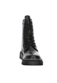 Botte de combat en cuir noir avec semelle épaisse, fermeture à lacets à l'avant et fermeture éclair latérale, vue de face sur fond blanc.