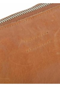 Brun läderplånbok i närbild, med en silverfärgad metallblixtlås, texturerad yta och synliga sömdetaljer.