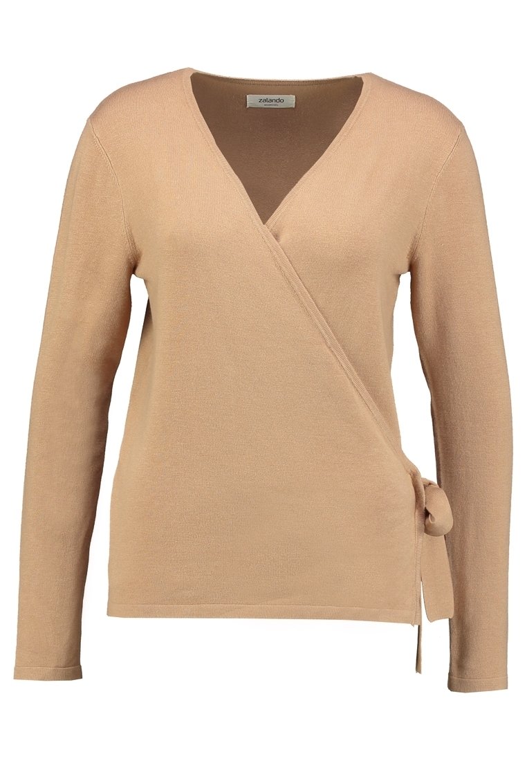 Pull en beige à enrouler avec des manches longues, un décolleté en V et un détail à nouer sur le côté. Tissu tricoté doux avec une texture lisse et un design simple.
