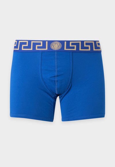 Boxers bleus pour hommes avec une large ceinture élastique ornée d'un motif doré clé grecque et un logo central tête de Méduse.