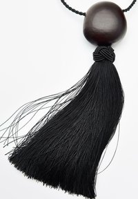 Decorazione a nappina nera con una perlina di legno arrotondata sulla parte superiore, dettagli intrecciati elaborati e lunghe frange fluide per aggiungere texture.