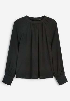 Sort langærmet bluse med rund halsudskæring og samlingsdetaljer. Har struktureret stof med små prikker og tapered manchetter.