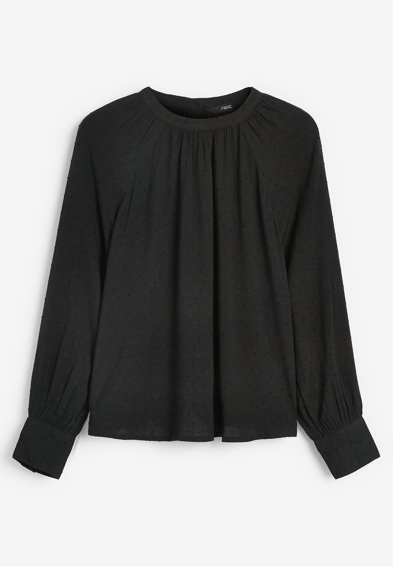 Blusa nera a maniche lunghe con scollatura tonda e dettagli arricciati. Presenta un tessuto texturizzato con piccole pois e polsini affusolati.
