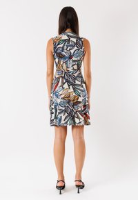 Abito senza maniche con motivo a foglia multicolore su sfondo bianco, con design svasato e lunghezza sopra il ginocchio.