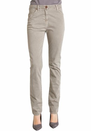 Beige slim-fit corduroy broek gedragen met grijze puntige hakken, getoond van taille tot voeten tegen een witte achtergrond.