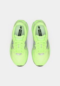 Neon yellow athletic shoes with a textured upper, reflective silver accents, and supported laces. Brand logo visible on the insoles.