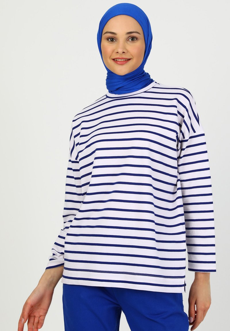 Top a maniche lunghe a righe in cotone bianco e blu navy, con scollatura rotonda e vestibilità rilassata, abbinato a pantaloni blu.