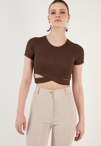 Barna bordázott rövid ujjú crop top, csavart kivágással, magas derekú bézs nadrággal, ami gombos záródással rendelkezik.