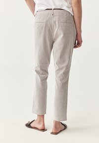 �Črtaste hlače v off-white in mornarski modri barvi, s prilagojenim krojem, zadnjimi žepi in gladkim, teksturiranim materialom. Dolžina hlač se konča nad gležnji.