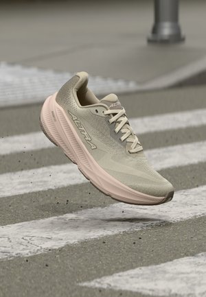 Light beige running shoe with thick sole and "ALTRA" branding, hovering above a street pedestrian crossing with white stripes.