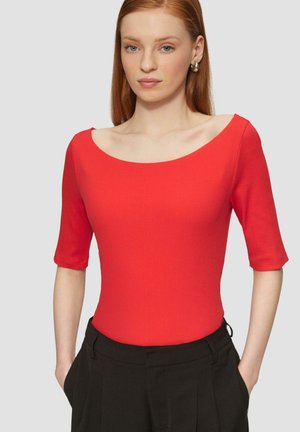 Czerwony bodysuit z prążkowanym wzorem, o szerokim dekolcie w serek i krótkich rękawach, w zestawieniu z czarnymi spódnicami plisowanymi. Gładka tekstura, dopasowany krój.
