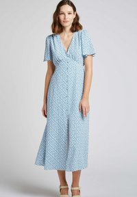 Robe florale bleu avec un décolleté en V, des manches courtes à volants et une fente à l'avant. Fabriquée en tissu léger, elle présente un corsage ajusté et une jupe fluide.