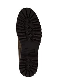 Semelle en caoutchouc noir avec des rainures profondes et des motifs croisés, attachée à un dessus en daim marron foncé, arborant un logo de marque visible.