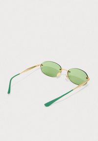 Occhiali da sole ovali verdi con montatura in metallo dorato e bracci accentati di verde. Presentano dettagli finemente lavorati sulla montatura e lenti colorate.