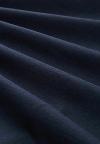 Tela azul marino con textura suave, drapeada en suaves pliegues, destacando un tejido uniforme y consistente sin patrones o adornos notables.