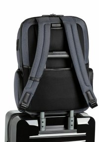 Sac à dos noir avec des bretelles en maille grise et des accents en cuir. Bretelles réglables se fixent à une poignée de valise en argent, présentant un design élégant.