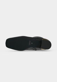 Semelle de chaussure en cuir noir avec bout carré, marque Valentino, taille 37 et accent doré sur le bord du talon.